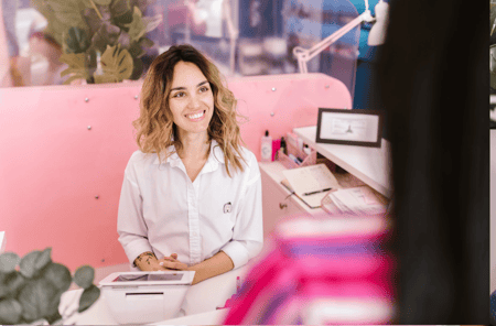 woman sitting at the front desk of a salon smiling
